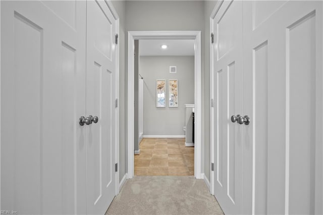 corridor featuring baseboards, visible vents, and light colored carpet