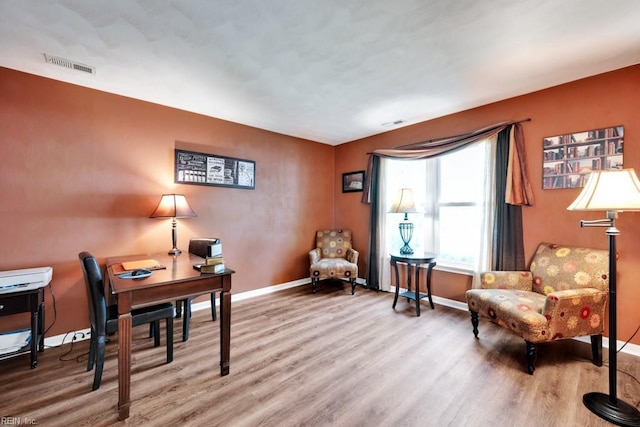 office with baseboards, visible vents, and wood finished floors