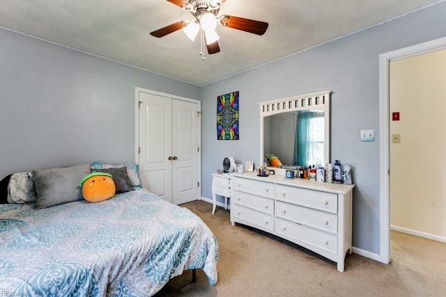 bedroom with baseboards, ceiling fan, light carpet, and a closet