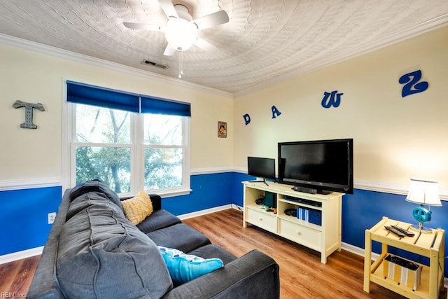living area featuring visible vents, ornamental molding, wood finished floors, baseboards, and a ceiling fan