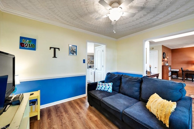 living area with baseboards, ornamental molding, ceiling fan, and wood finished floors