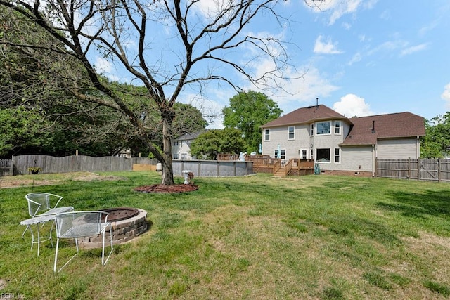view of yard featuring a fenced in pool, a fenced backyard, a fire pit, and a wooden deck