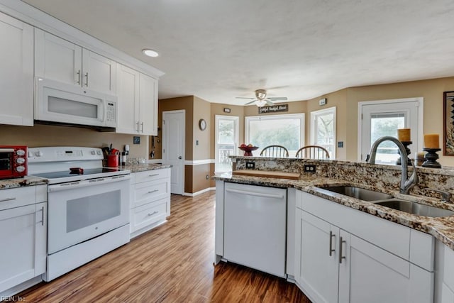 kitchen with ceiling fan, a sink, light wood finished floors, white appliances, and white cabinetry