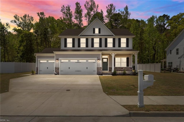 view of front of property with fence, stone siding, a front yard, and concrete driveway