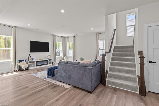 living area featuring recessed lighting, a healthy amount of sunlight, wood finished floors, and stairway