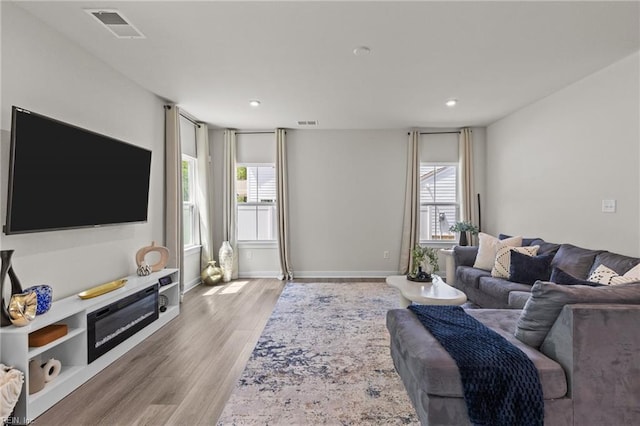 living area featuring recessed lighting, visible vents, a wealth of natural light, and light wood-type flooring