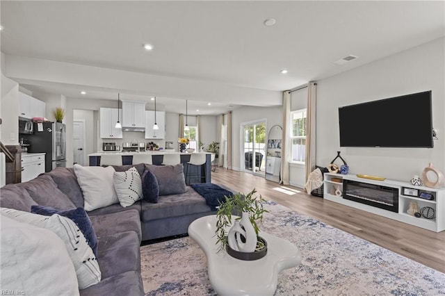 living room with recessed lighting, light wood-type flooring, and visible vents