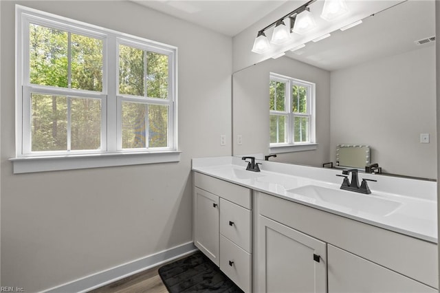 full bath featuring baseboards, visible vents, a sink, and wood finished floors