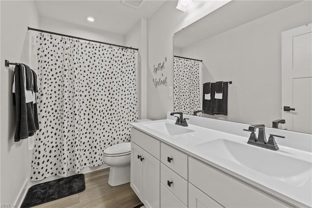 full bathroom featuring double vanity, a sink, wood finished floors, and toilet