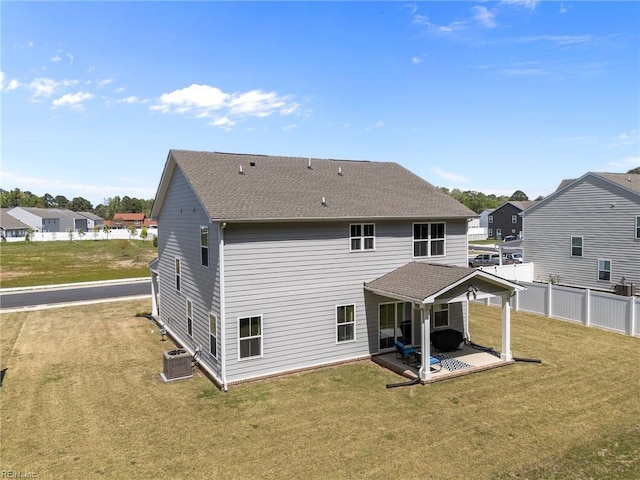 back of property with a lawn, a patio area, central air condition unit, and fence