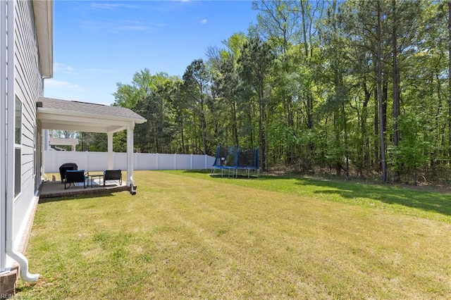 view of yard with a fenced backyard, a trampoline, and a patio area