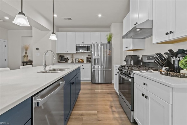 kitchen featuring visible vents, under cabinet range hood, white cabinets, a sink, and appliances with stainless steel finishes