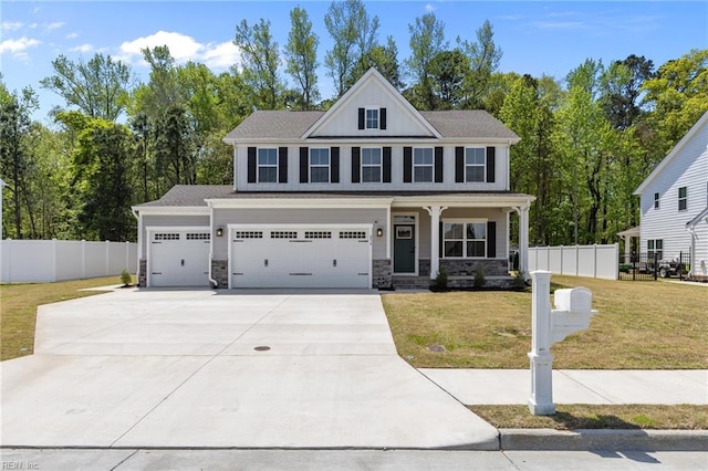 craftsman-style house with driveway, fence, covered porch, and a front yard