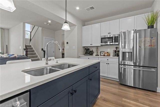 kitchen featuring appliances with stainless steel finishes, a sink, light countertops, white cabinetry, and visible vents