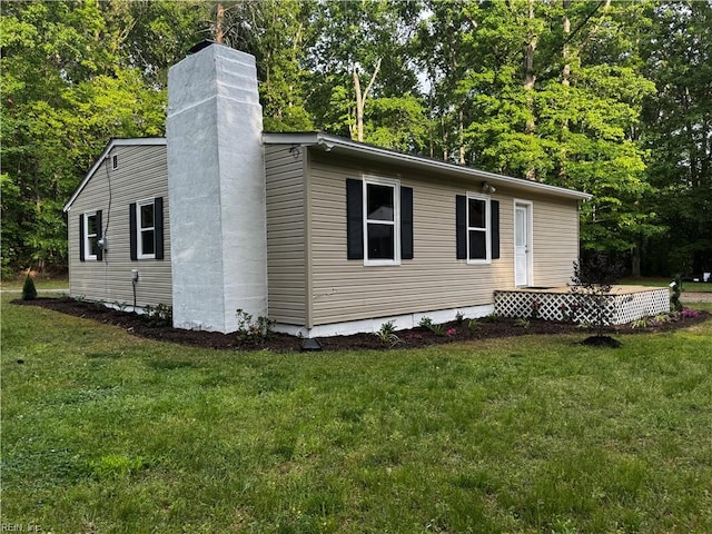 view of side of property featuring a lawn and a chimney