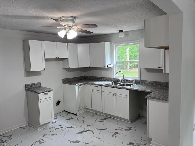 kitchen featuring white cabinets, ceiling fan, a sink, a textured ceiling, and marble finish floor