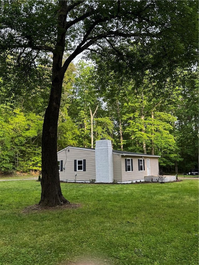 view of front facade featuring a chimney and a front lawn