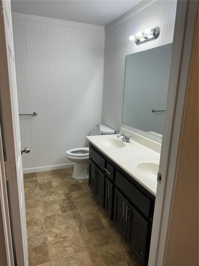 bathroom featuring double vanity, toilet, wood walls, and stone finish flooring