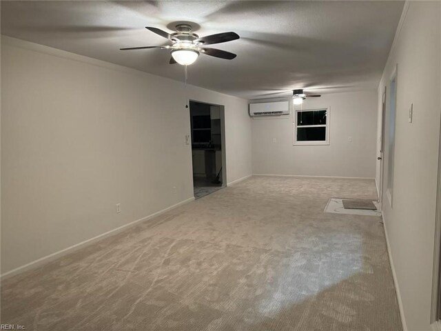 spare room with carpet floors, ceiling fan, a wall unit AC, and baseboards