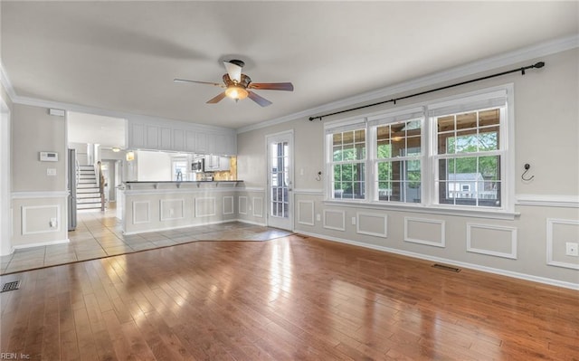 721 Greenwing Dr, Chesapeake, VA 23323 - unfurnished living room with crown molding, ceiling fan, wainscoting, a decorative wall, and light wood-style flooring