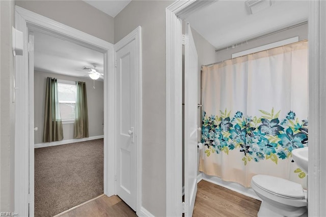 bathroom with visible vents, wood finished floors, toilet, ceiling fan, and shower / bathtub combination with curtain