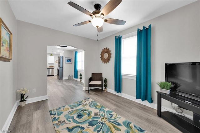 sitting room with baseboards, arched walkways, a ceiling fan, and wood finished floors