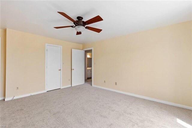 spare room featuring light colored carpet, baseboards, and ceiling fan