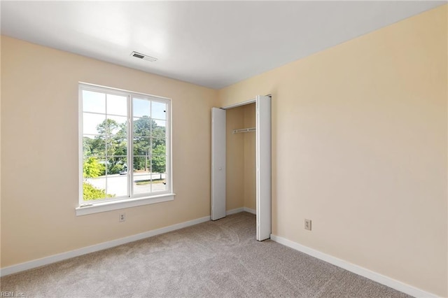 unfurnished bedroom featuring light colored carpet, baseboards, visible vents, and multiple windows