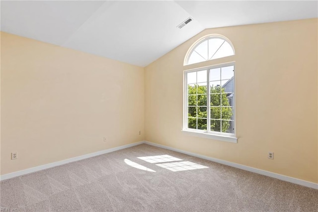 spare room with carpet, vaulted ceiling, baseboards, and visible vents