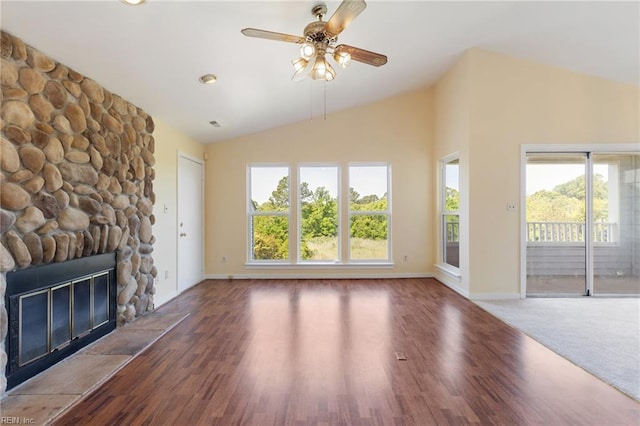 unfurnished living room with wood finished floors, baseboards, a stone fireplace, ceiling fan, and lofted ceiling