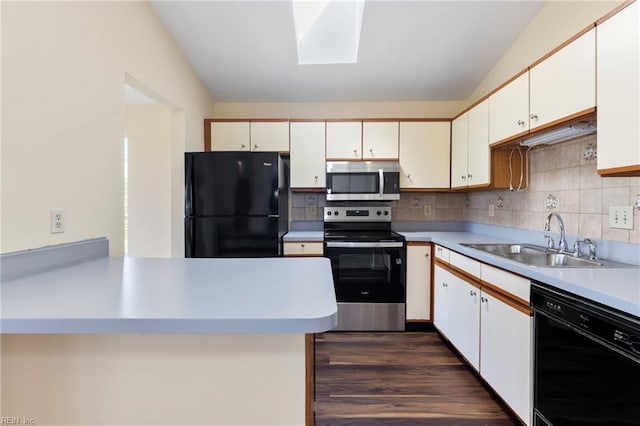 kitchen featuring white cabinetry, a skylight, black appliances, and a sink
