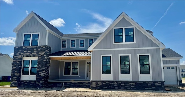 modern farmhouse featuring a garage, covered porch, a standing seam roof, board and batten siding, and metal roof