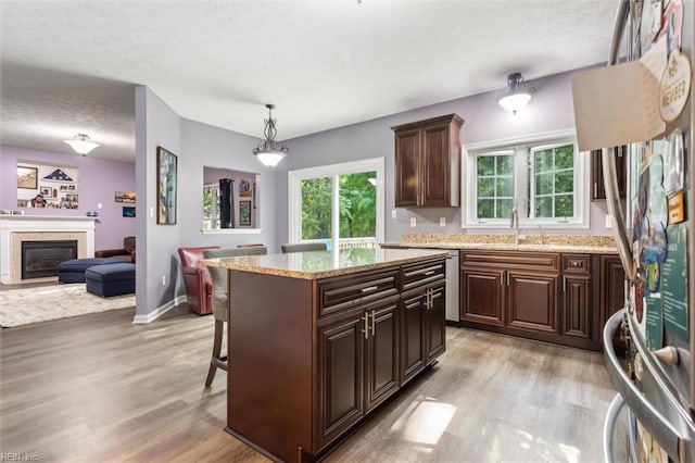 kitchen with a textured ceiling, light wood-style flooring, a sink, appliances with stainless steel finishes, and open floor plan