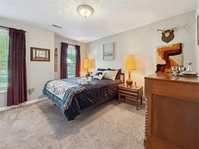 bedroom featuring light carpet, a textured ceiling, and baseboards