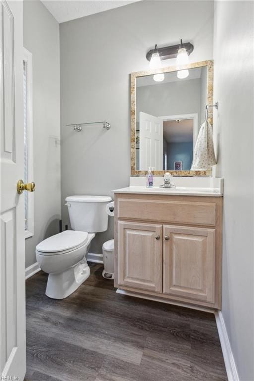 bathroom featuring toilet, wood finished floors, vanity, and baseboards
