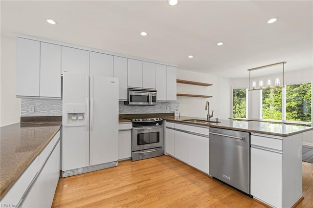 kitchen with stainless steel appliances, a sink, a peninsula, open shelves, and recessed lighting