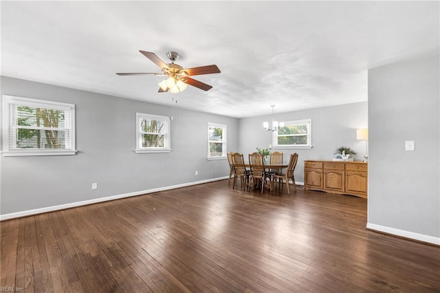 dining area featuring dark wood-type flooring, baseboards, and ceiling fan with notable chandelier
