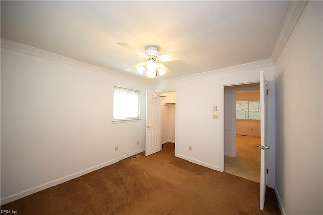 unfurnished bedroom featuring baseboards, multiple windows, ornamental molding, and carpet floors