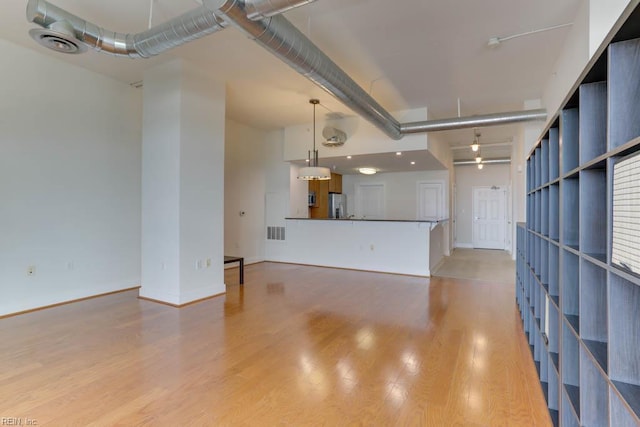 unfurnished living room with baseboards, visible vents, and light wood finished floors