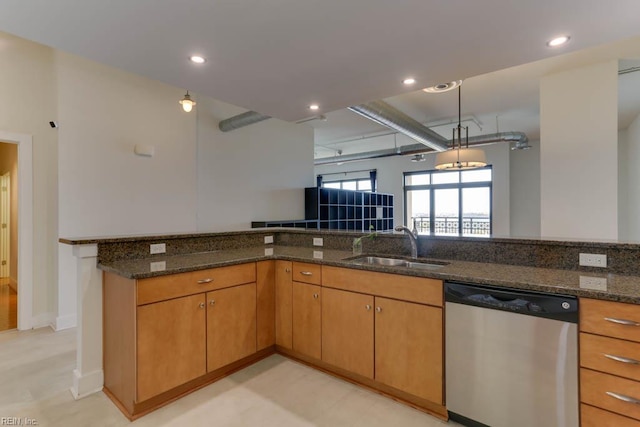 kitchen featuring hanging light fixtures, stainless steel dishwasher, a sink, dark stone countertops, and recessed lighting