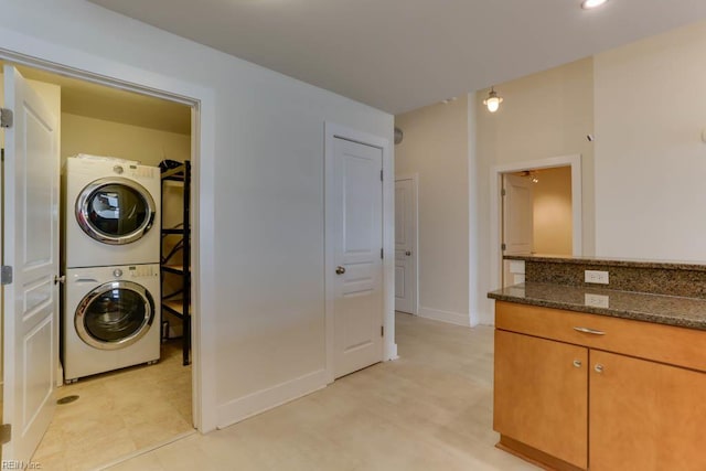 washroom with stacked washer / drying machine, baseboards, laundry area, and light floors