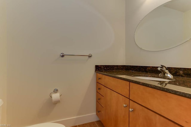 bathroom with vanity, baseboards, toilet, and tile patterned flooring