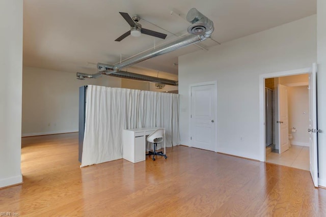 interior space featuring a ceiling fan, baseboards, and wood finished floors