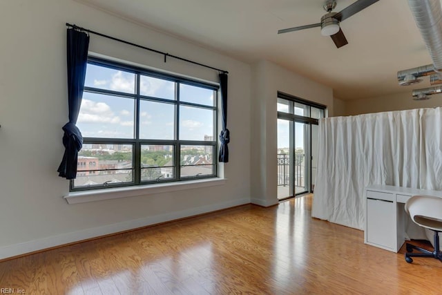 unfurnished room with baseboards, a ceiling fan, and wood finished floors