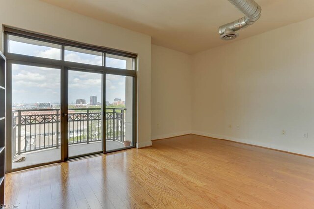 spare room with a view of city, baseboards, visible vents, and light wood-style flooring