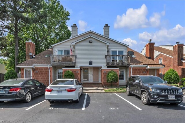 5117 Walkers Grant Ln Unit A, Virginia Beach, VA 23455 - view of property with brick siding, uncovered parking, a balcony, and a chimney