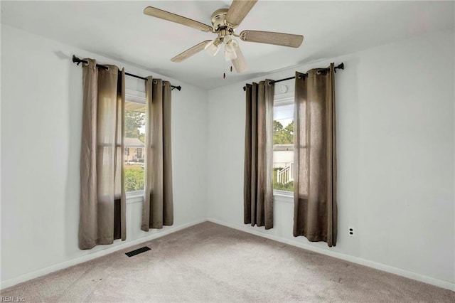 carpeted spare room with visible vents, a ceiling fan, baseboards, and a healthy amount of sunlight
