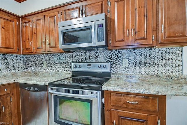 kitchen with light stone countertops, stainless steel appliances, decorative backsplash, and brown cabinets