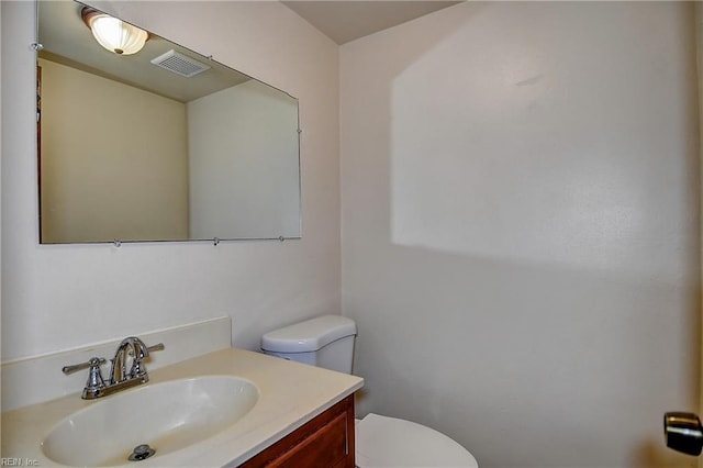 bathroom with vanity, toilet, and visible vents