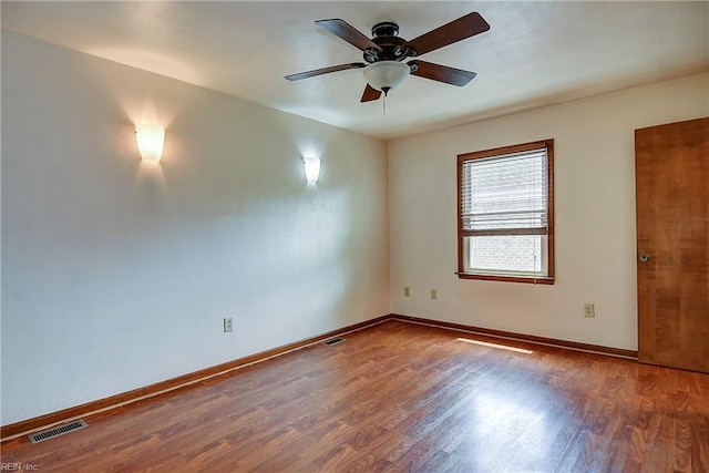 empty room with visible vents, wood finished floors, baseboards, and ceiling fan